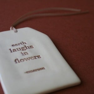 Image of ceramic quote tag - earth laughs
